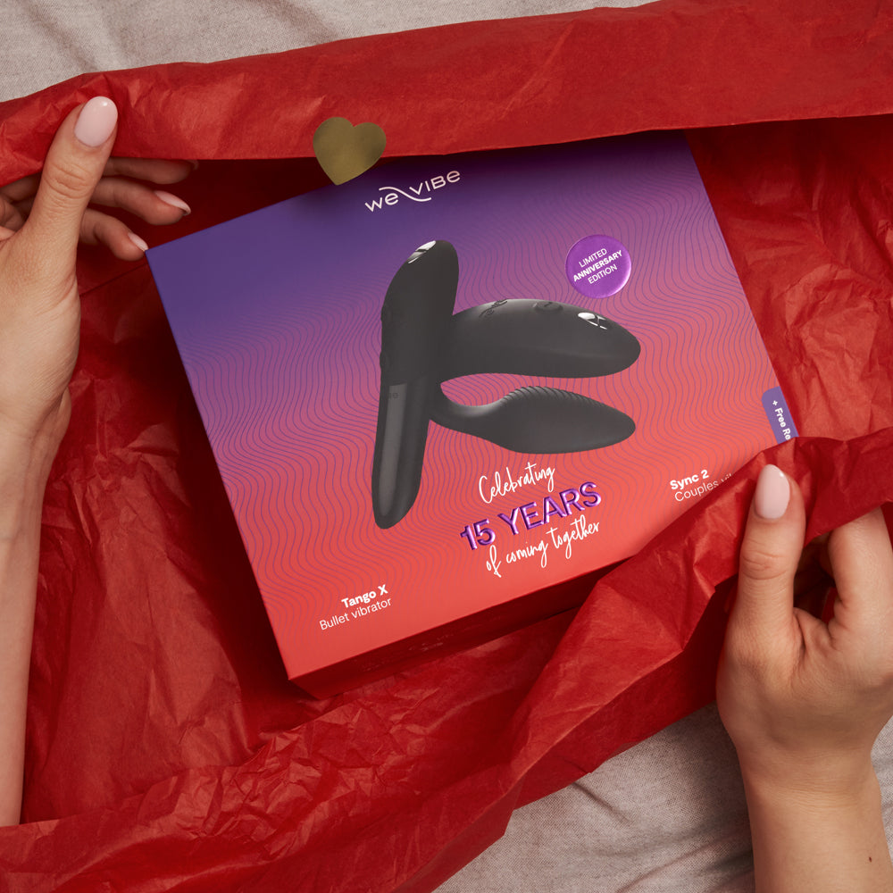 Someone unwraps a gift containing the We-Vibe 15-Year Anniversary Collection, consisting of the Tango X and Sync 2 vibrators.