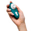 A hand holds the travel-sized Womanizer Liberty 2 Clitoral Stimulator to show its scale.