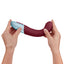 FemmeFunn - Lola G - ergonomically curved, flexible G-spot vibrator has an angled head & a wavy rippled texture on a soft liquid silicone body. Maroon, in hand and bending