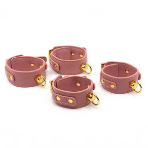 Sevanda 5-Piece Pink Bondage Set includes 4 wrist/ankle cuffs, a collar w/ chain leash + a blindfold & is made from vegan pink faux leather + luxurious gold metal. Cuffs.